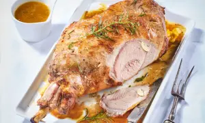 Gigot d'agneau rôti, doré et juteux, garni de romarin frais. Un délice pour la cuisson parfaite.