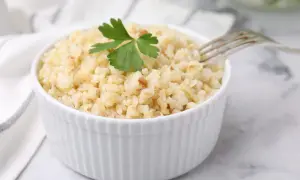 Un bol de boulgour cuit, garni d'une feuille de persil, prêt à être dégusté. La cuisson du boulgour est simple et rapide.