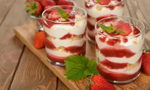 Délicieux tiramisu fraise en verrines, alternant couches de crème, biscuits émiettés et coulis de fraises, garni de fruits frais et de menthe.