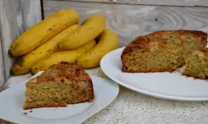Tranches de gâteau yaourt banane moelleux, avec des bananes fraîches en arrière-plan. Un délice simple et réconfortant.