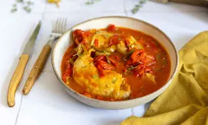 Un plat de poulet basquaise, préparé au Cookeo, servi dans un bol avec des poivrons rouges et verts, garni de thym.