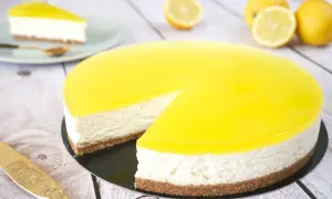 Cheesecake citron mascarpone, un délice jaune vif sur fond de bois. Une part est déjà servie.
