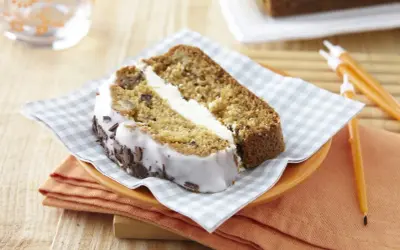 Tranche de carrot cake moelleux avec glaçage blanc et copeaux de chocolat. Un délice à savourer !