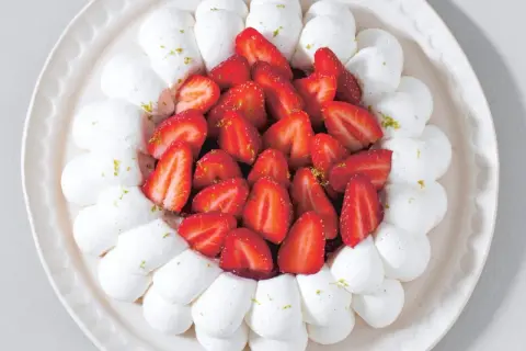 Délicieuse recette avec fraises fraîches facile : meringue aérienne et fruits rouges sur une assiette décorative.