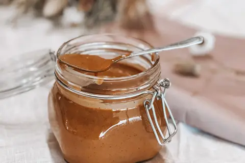 Un pot de praliné noisette maison, prêt à être dégusté. Une recette simple pour un délice gourmand.