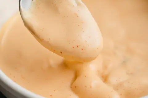 Une cuillère de sauce Big Mac crémeuse, parsemée de petites touches de paprika, prête à être dégustée.