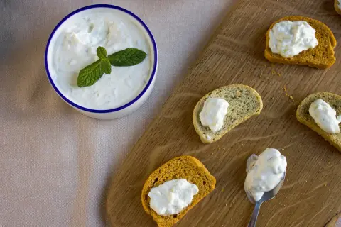 Un bol de tzatziki frais garni de menthe, servi avec des toasts. Une recette facile à partager !