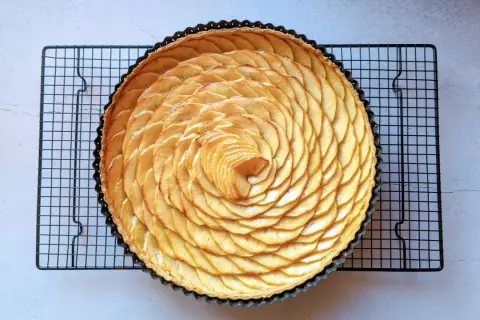 Tarte aux pommes recette de maman, magnifiquement décorée de fines tranches de pommes disposées en spirale sur une pâte dorée.