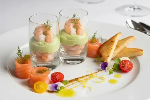 Une délicieuse entrée froide : crevettes et avocat en verrine, saumon roulé, toasts grillés, tomates cerises et fleurs comestibles.