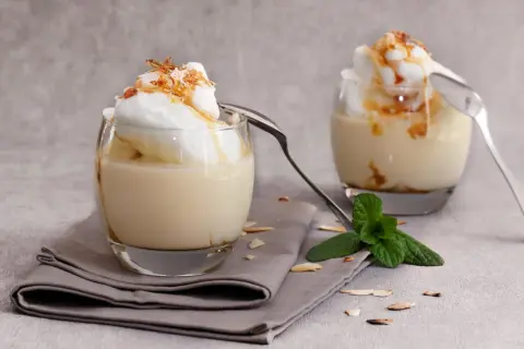 Deux verres de délicieux oeufs à la neige, surmontés de crème et de caramel, avec une touche de menthe fraîche.