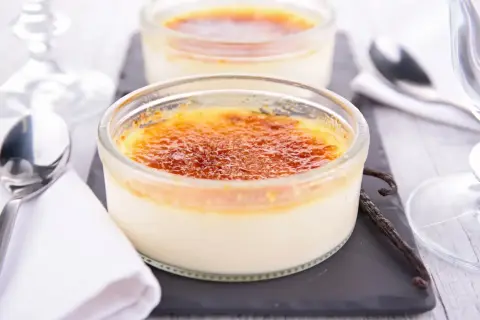 Deux délicieux crèmes brûlées, leur croûte caramélisée craquante, prêts à être dégustés avec une cuillère et une gousse de vanille.