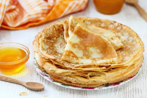 Pile de crêpes dorées, accompagnées d'un bol de miel. Parfait pour une recette pâte à crêpe facile sans repos.