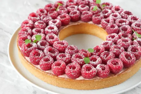 Une magnifique tarte à la framboise facile, garnie de fruits rouges frais et saupoudrée de sucre glace. Parfaite pour un dessert gourmand.