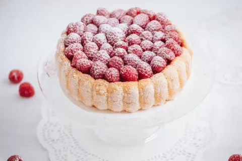 Charlotte aux framboises, un délice léger et fruité, ornée de fruits rouges frais et saupoudrée de sucre glace.
