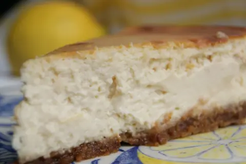 Tranche de cheesecake ricotta citron, crémeuse et légère, sur une assiette décorée de citrons.