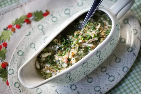 Sauce ravigote fraîche et acidulée, garnie de ciboulette ciselée, dans un saucier décoré.