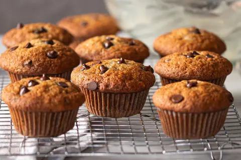 Muffins banane chocolat dorés et moelleux, parsemés de pépites de chocolat, refroidissant sur une grille.