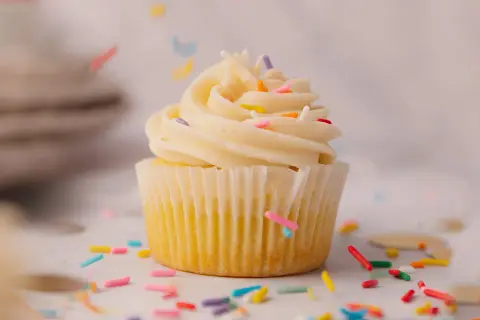 Un cupcake vanille avec glaçage crémeux et vermicelles colorés, parfait pour une recette de cupcake facile et festive.