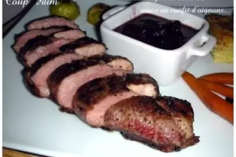 Magret de canard tranché, servi avec une sauce au confit d'oignons. Un délice pour les gourmands.