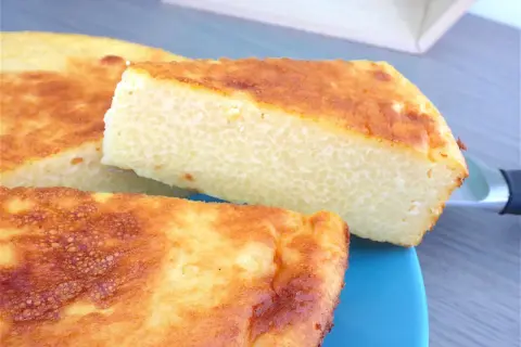 Un gâteau arabe semoule extra fine, doré et moelleux, servi sur une assiette bleue. Sa texture légère promet un délice.