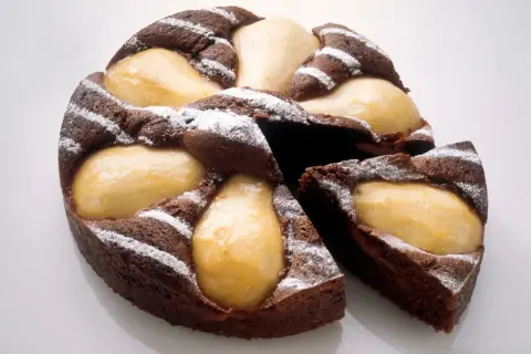 Gâteau poire chocolat, un délice moelleux parsemé de sucre glace, avec des poires fondantes incrustées dans la pâte.