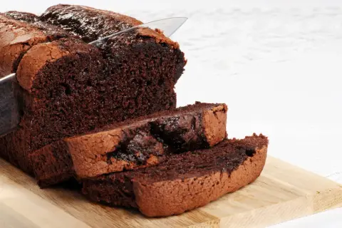 Un délicieux gâteau au chocolat sans beurre, coupé en tranches sur une planche en bois. Sa texture moelleuse et son goût intense invitent à la gourmandise.