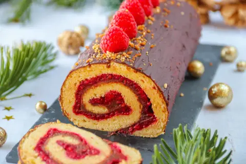 Bûche au chocolat et framboises, parfaite pour une recette de fête. Décorée de fruits rouges et de noisettes concassées.