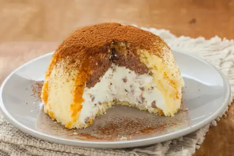 Gâteau glacé en forme de dôme, garni de crème et de chocolat, saupoudré de cacao. Parfait pour une recette génoise.