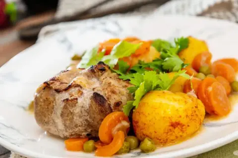 Paupiette de veau savoureuse, accompagnée de pommes de terre rôties, carottes et petits pois. Un plat réconfortant pour la cuisson.