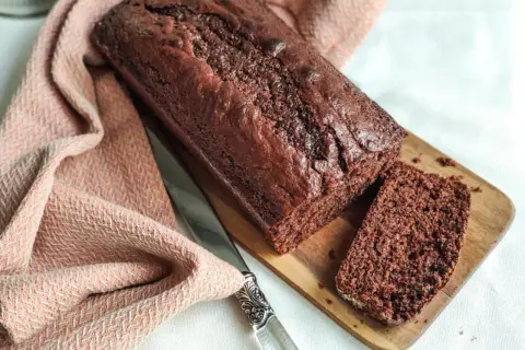 Un délicieux gâteau yaourt chocolat, moelleux et gourmand, prêt à être dégusté. Une tranche est déjà coupée.