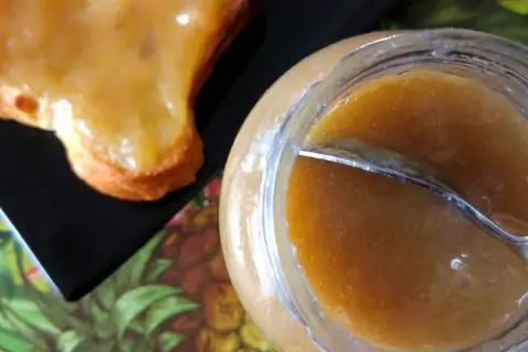 Un pot de confiture rhubarbe banane et une tartine généreusement garnie. Une gourmandise maison prête à être dégustée.