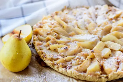 Délicieuse tarte aux poires, garnie de fruits frais et saupoudrée de sucre glace. Un délice pour les yeux et les papilles.