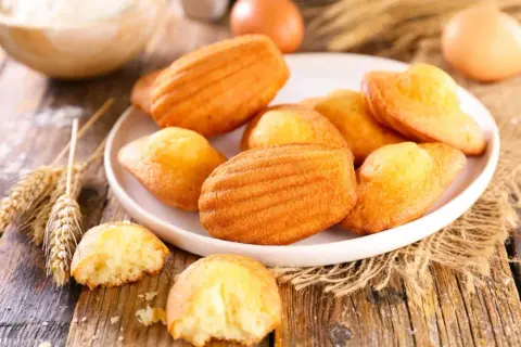 Assiette de madeleines dorées, prêtes à être dégustées. Une recette simple pour un goûter parfait.