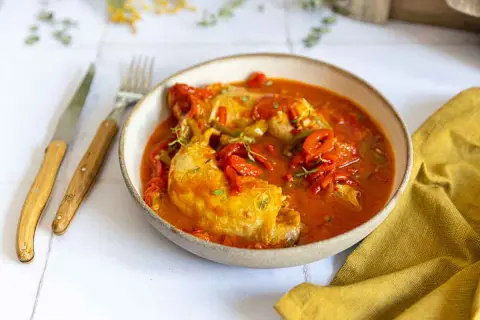 Un plat de poulet basquaise, préparé au Cookeo, servi dans un bol avec des poivrons rouges et verts, garni de thym.