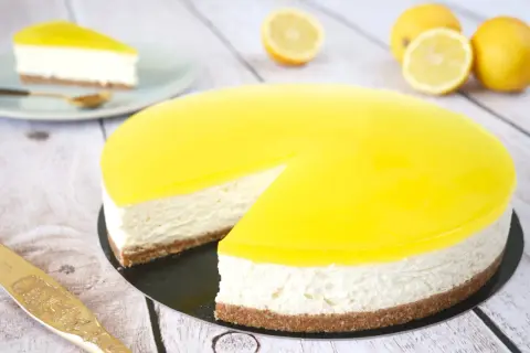 Cheesecake citron mascarpone, un délice jaune vif sur fond de bois. Une part est déjà servie.