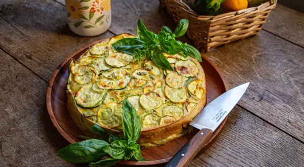 Un délicieux cake à la courgette, garni de basilic frais, prêt à être découpé.