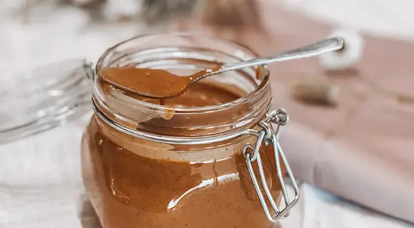 Un pot de praliné noisette maison, prêt à être dégusté. Une recette simple pour un délice gourmand.