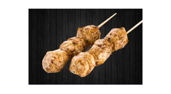 Deux brochettes de boulettes de poulet yakitori grillées, sur fond de bois sombre.