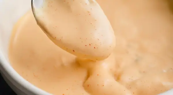 Une cuillère de sauce Big Mac crémeuse, parsemée de petites touches de paprika, prête à être dégustée.