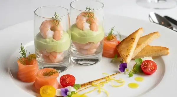 Une délicieuse entrée froide : crevettes et avocat en verrine, saumon roulé, toasts grillés, tomates cerises et fleurs comestibles.