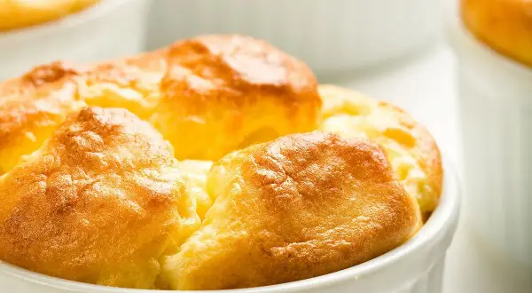 Soufflés au fromage dorés et gonflés dans leurs ramequins, prêts à être dégustés. Une recette simple pour un plat aérien.