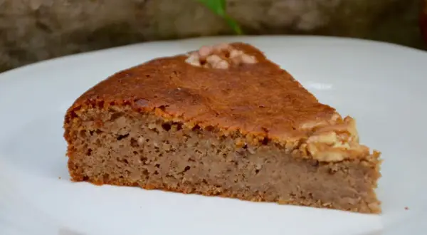 Tranche de gâteau aux noix moelleux, garnie d'une noix entière. Parfait pour une recette facile et gourmande.