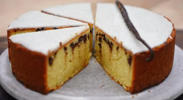 Gâteau poudre d'amande facile et rapide, avec glaçage blanc et éclats de chocolat. Une gousse de vanille décore ce délice.