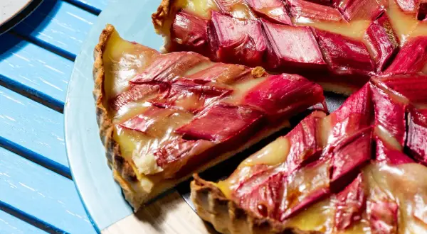 Tarte à la rhubarbe sur pâte feuilletée, garnie de fruits rouges et d'une crème dorée. Un délice estival.