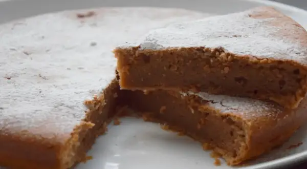 Un délicieux gâteau à la crème de marron, saupoudré de sucre glace, avec une part coupée pour révéler sa texture moelleuse.