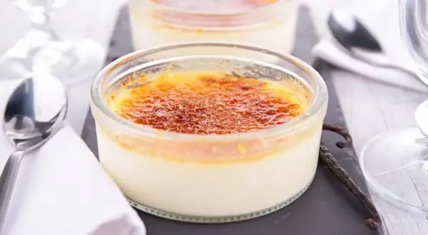 Deux délicieux crèmes brûlées, leur croûte caramélisée craquante, prêts à être dégustés avec une cuillère et une gousse de vanille.