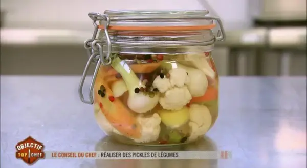 Un bocal de pickles de légumes colorés, comme ceux préparés par un Top Chef, rempli de chou-fleur, carottes et oignons.