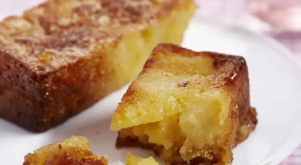 Un gâteau aux pommes moelleux et ultra rapide, doré et appétissant, servi sur une assiette blanche.