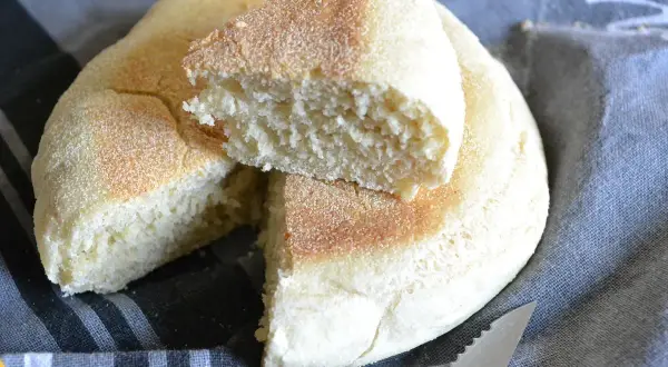 Un pain à la poêle, moelleux et doré, coupé en deux pour révéler sa mie aérée. Parfait pour le petit-déjeuner.