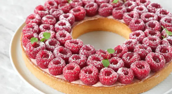 Une magnifique tarte à la framboise facile, garnie de fruits rouges frais et saupoudrée de sucre glace. Parfaite pour un dessert gourmand.